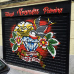 Graffiti en la persiana del estudio de tatuajes Kronen en Vallecas