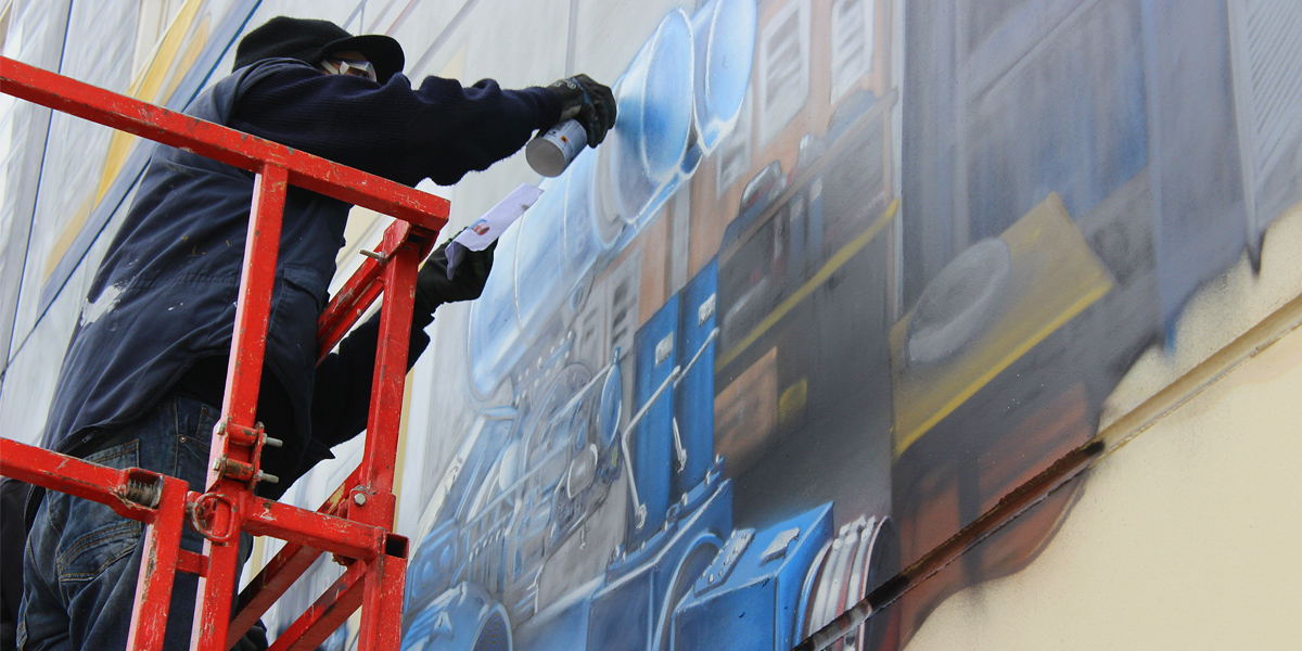 Grafitero pintando trampantojo de gran tamaño